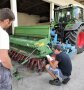Person kniet neben Sämaschine