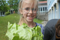Kind hält Blattsalatkopf